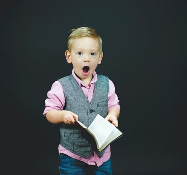 Young boy holding a book and looking like he's wowed!